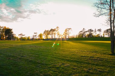 Gün batımında futbol sahası olan bir park, akşam aktiviteleri ve spor için huzurlu bir ortam sunuyor.