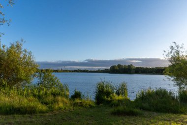 A wild landscape with natural vegetation surrounds the lake, creating an atmosphere of pristine nature and tranquility clipart