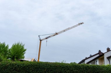 Bir inşaat vinci yerleşim alanının üzerinde süzülür, şehir manzarasındaki büyüme ve dönüşümü sembolize eder