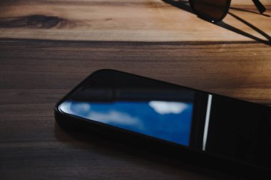 Ahşap bir masaya yerleştirilmiş bir akıllı telefon.