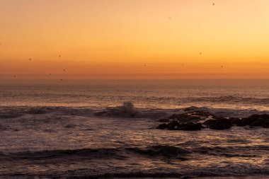 Atlantik Okyanusu kıyısında turuncu gökyüzü olan alacakaranlık.
