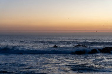 Atlantik Okyanusu kıyısında turuncu gökyüzü olan alacakaranlık.
