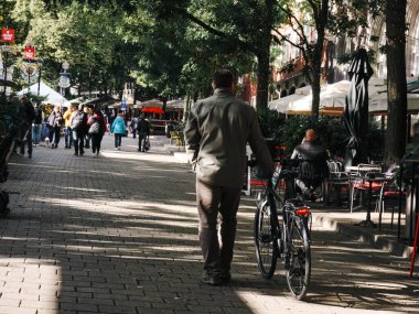 Avrupa kaldırım taşı sokağında bisikletlerin yanından geçen bir adam