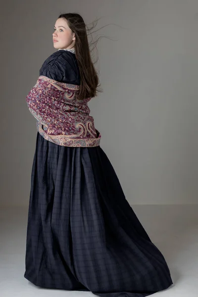 スタジオを背景にヴィンテージレーストリムと青の綿のドレスを着て若いビクトリア朝の女性 ストックフォト