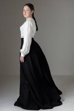 A young Victorian or Edwardian woman wearing a white linen Garibaldi blouse and black skirt  clipart