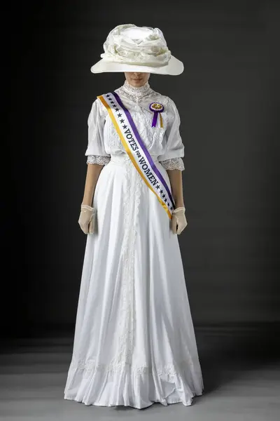 stock image American Victorian or Edwardian Suffragette wearing the historically accurate purple and gold sash and rosette and protesting for women's voting rights against a plain studio backdrop
