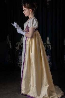 Gece kıyafeti giyen bir naip kadın, nakışlı bir elbise, uzun bir spencer ve eldiven.