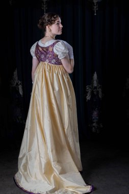 Gece kıyafeti giyen bir naip kadın, nakışlı bir elbise, uzun bir spencer ve eldiven.