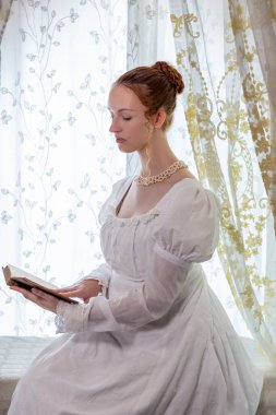 Beyaz pamuklu elbise giyen ve arkadan ışıklandırılmış dantel perdelerle çevrili bir naip kadın.