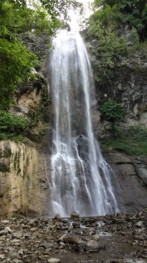 A scenic waterfall cascading down a rocky cliff surrounded by lush greenery. clipart