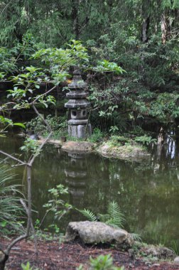 A view of the pond with sculpture beyond in the Morikami Japanese Botanical Gardens in Boynton Beach Florida on a sunny summer day. clipart