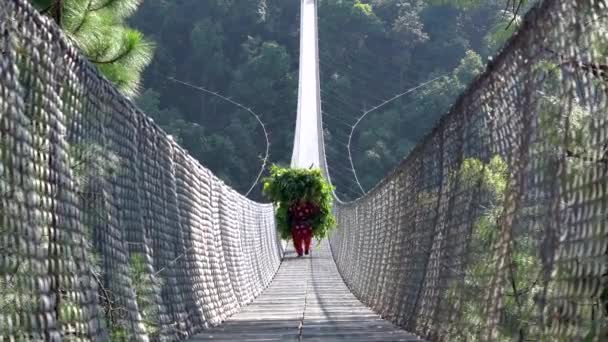 Ένας Νεπαλέζος Που Κουβαλάει Βαρύ Φορτίο Και Διασχίζει Κρεμαστή Γέφυρα — Αρχείο Βίντεο