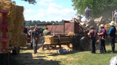 Kinzers, Pennsylvania - 18 Ağustos 2022: Rough and Tumble Thresherman 's Reunion' da eski harman makinelerinin buhar gücüyle kullanımını göstermek ve makineden çıkınca samanı balyalamak.