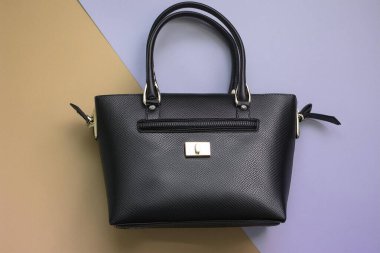Ahşap arka planda şık siyah deri bir kadın çantası..