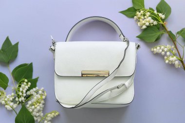 Beyaz çiçekli, eflatun kaplamalı beyaz bir çanta. Bahar mevsimi modası. düz üst görünüm.