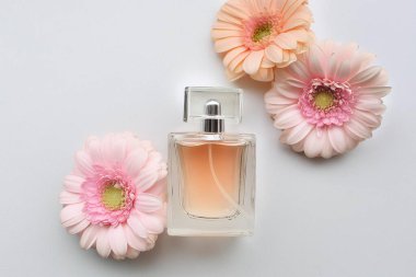 Temel parfüm şişesi ve beyaz arka planda güzel çiçekler.