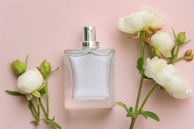 Pembe arka planda parfüm şişesi ve çiçekler