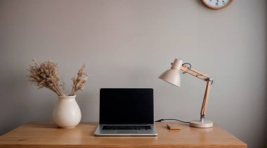 Gri duvarın yanındaki beyaz masada dizüstü bilgisayarı, lambası, fincanı ve dekoru olan şık bir iş yeri. Yüksek kalite fotoğraf