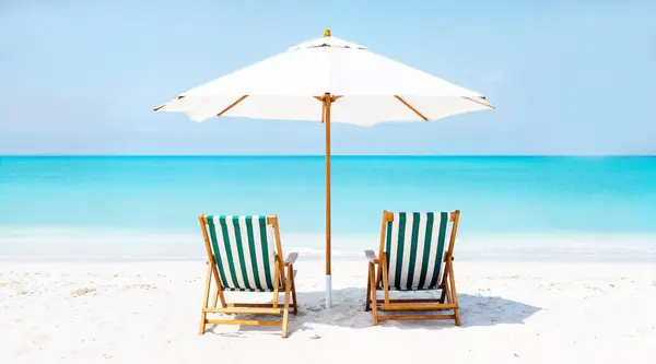 Güzel tropik ada manzarası, iki güneş yatağı, dinlenme yerleri, palmiye ağacının altındaki şemsiye. Beyaz kum, ufukta deniz manzarası, cennet mavisi gökyüzü. İlham verici bir sahil oteli. Yüksek kalite fotoğraf