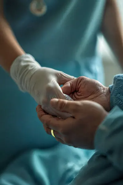 Bir hemşire, yaşlı bir hastayı nazikçe bir hastane yatağında tutuyordu. Yüksek kalite fotoğraf