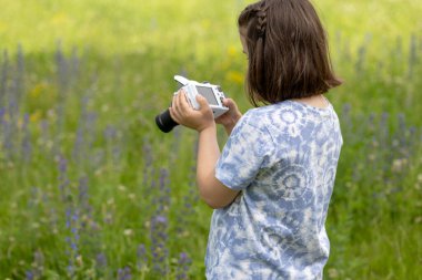 Küçük bir kız kamerayla doğanın fotoğraflarını çekiyor. Yüksek kalite fotoğraf