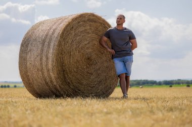 Tarım alanında saman balyasına yaslanan bir adam. Yüksek kalite fotoğraf