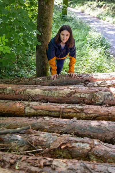 stock image  Woman tourist climbs up the wooden logs in the forest. High quality photo