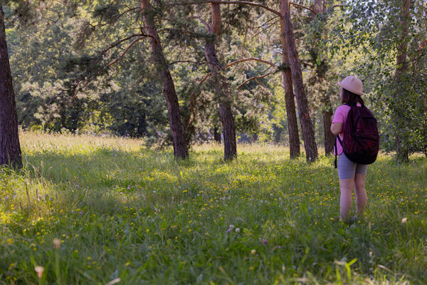 Little tourist girl is going on a hike. She has a hat and a backpack.High quality photo