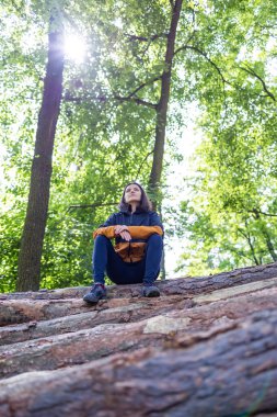  Ormandaki ağaç kütüklerinde oturan kadın turist. Yüksek kalite fotoğraf