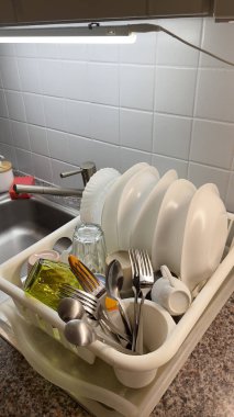 Çeşitli temiz bulaşıklar, bardaklar ve aletler mutfak lavabosunun yanındaki askıda dinleniyor. Yemek hazırlayıp eğlendikten sonra temizlik sürecini gösteren tipik bir manzara..