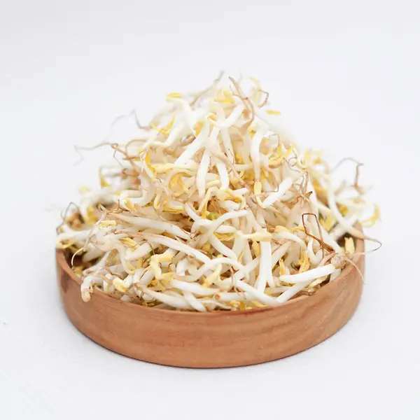 Beyaz arka planda izole edilmiş ahşap kasede fasulye filizleri.