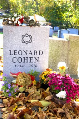 Solemn Image of Leonard Cohen's Gravestone, Adorned with Flowers, Stones, and Colorful Tributes. The Site Reflects Respect and Remembrance for the Legendary Singer, Songwriter, and Poet. clipart