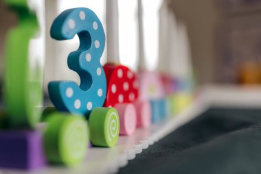 A wooden candle holder shaped like a train for birthdays, with the number 3 in focus. Birthday in Norway clipart