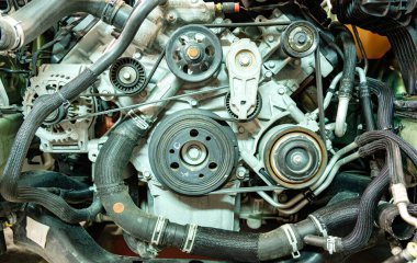 Kemerlerin, makaraların ve diğer mekanik parçaların montajını detaylandıran karmaşık bir araba motorunun yakın plan görüntüsü, genellikle bir aracın motor bölümünde bulunur..