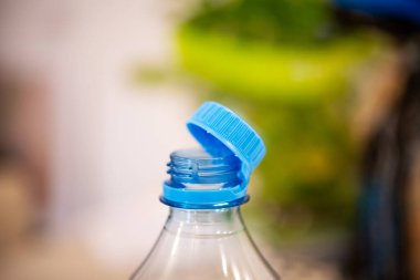 Temiz bir şişeye bağlı mavi plastik kapağı yakalama odaklı bir çekim, 2024 yazından itibaren kirliliği azaltma amaçlı yeni AB yönetmeliklerinin altını çiziyor.