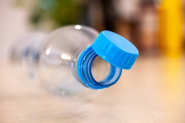 Yeni zorunlu mavi başlıklı plastik bir su şişesinin yakın plan görüntüsü, 2024 yazında yürürlüğe girecek olan AB yönetmeliklerini gösteriyor.