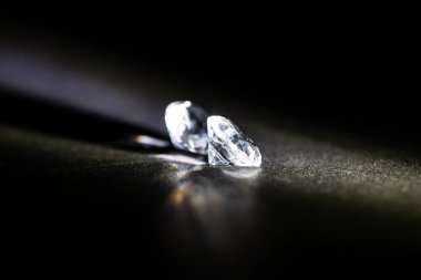 İki el değmemiş, monte edilmemiş elmas gölgeli bir arkaplana karşı ışıltılı bir ışık saçıyor, lüks ve lüks piyasanın simgesi. Bu görüntü zenginliğin ve ayrıcalığın özünü yakalar..