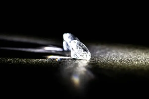 stock image A sharply detailed photograph captures the intricate facets of a brilliant cut diamond, placed on a dark textured surface under dramatic lighting. This image conveys luxury and high-net-worth status without depicting any persons.