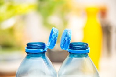 Görüntü, AB 'nin plastik atıkları azaltma yönergesi kapsamında sürdürülebilirlik çabalarını yansıtan şeffaf plastik şişelerin mavi kapaklarını yakalıyor.