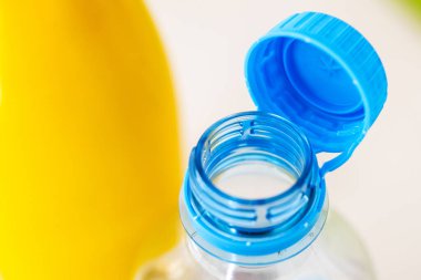 Net bir plastik şişenin açık mavi kapaklı yakın plan görüntüsü, canlı sarı bir arkaplana karşı, AB çevre standartlarına uyduğunu gösteriyor.