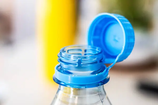 stock image A detailed close-up of a blue tethered cap, attached to a clear plastic bottle, exemplifying environmental conservation efforts according to the EU Directive. The cap helps in preventing litter.