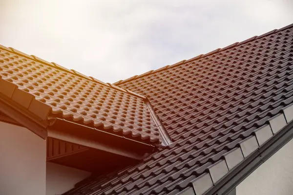 stock image Multi-pitched roof featuring terracotta tiles under soft sunlight, showcasing contemporary architectural design and structural elegance suited for new constructions.