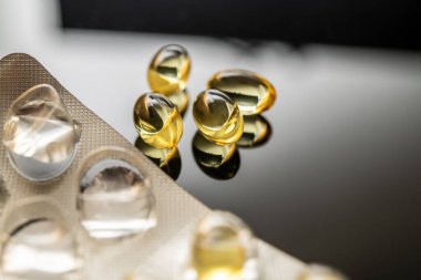 D vitamini ve Omega-3 balık yağı takviyeleri de dahil olmak üzere sarı şeffaf kapsüllerin düzenlenmesi, sağlık faydalarını ve sağlıklı yaşam odaklı tüketiciler için besin değerini yansıtıyor.