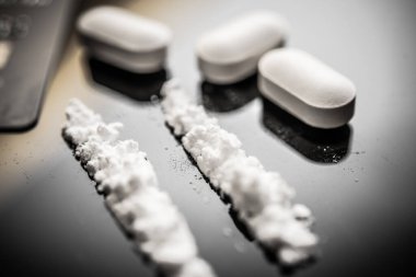 Beyaz haplara ve toz haline getirilmiş maddelere yakın çekim, opioid kullanımının tehlikelerini ve büyüyen fentanil krizinin dünya çapında toplumları ve sağlık liderlerini etkilediğini gösteriyor..