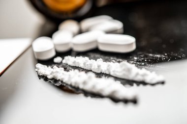 Reçeteli opioid tabletlerinin yanında fentanil tozu çizgileri yer almakta olup, çağdaş sağlık senaryolarında opioid kullanımı ve bağımlılığa ilişkin artan endişeleri göstermektedir..