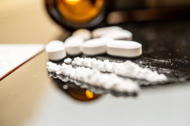 Fentanil de dahil olmak üzere, opioidlerin yakın çekim görüntüsü, yansıtıcı bir yüzeyde haplar ve toz gibi çeşitli şekillerde sunulmuştur, devam eden opioid krizini ve bunun etkilerini göstermektedir..