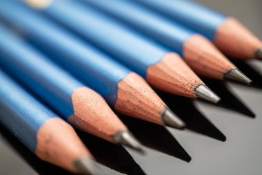 Keskinleştirilmiş uçlu mavi renkli kalemler, parlak siyah bir yüzeyi yansıtıyor. Sanat, eğitim ve yaratıcı projeler için uygundur..