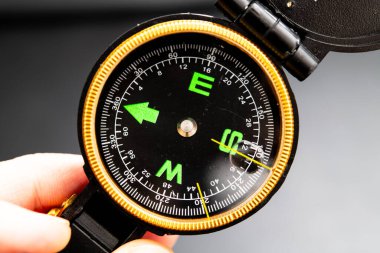 Hand-held vintage compass highlighting navigation, direction finding, and outdoor adventure tools, perfect for hikers, campers, and explorers embracing nature's wonders and creating memorable journeys. clipart