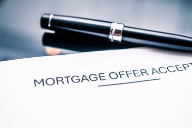 Bir ipotek teklifinin yakın plan kabul belgesinin yanı sıra bir kalem, mali kararları temsil eden, ev satın alma süreçleri, kredi anlaşmaları, emlak yatırımları ve mortgage sözleşmelerine bağlılık.