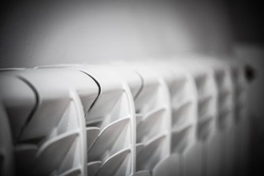 Modern ısıtma verimliliği, ev konforu çözümleri ve çağdaş iç dekorasyon ve enerji verimliliği için parlak tasarım unsurları gösteren şık beyaz bir radyatörün yakın çekimi.